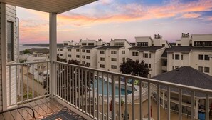 Un balcón con vista a una piscina y edificios cercanos.
