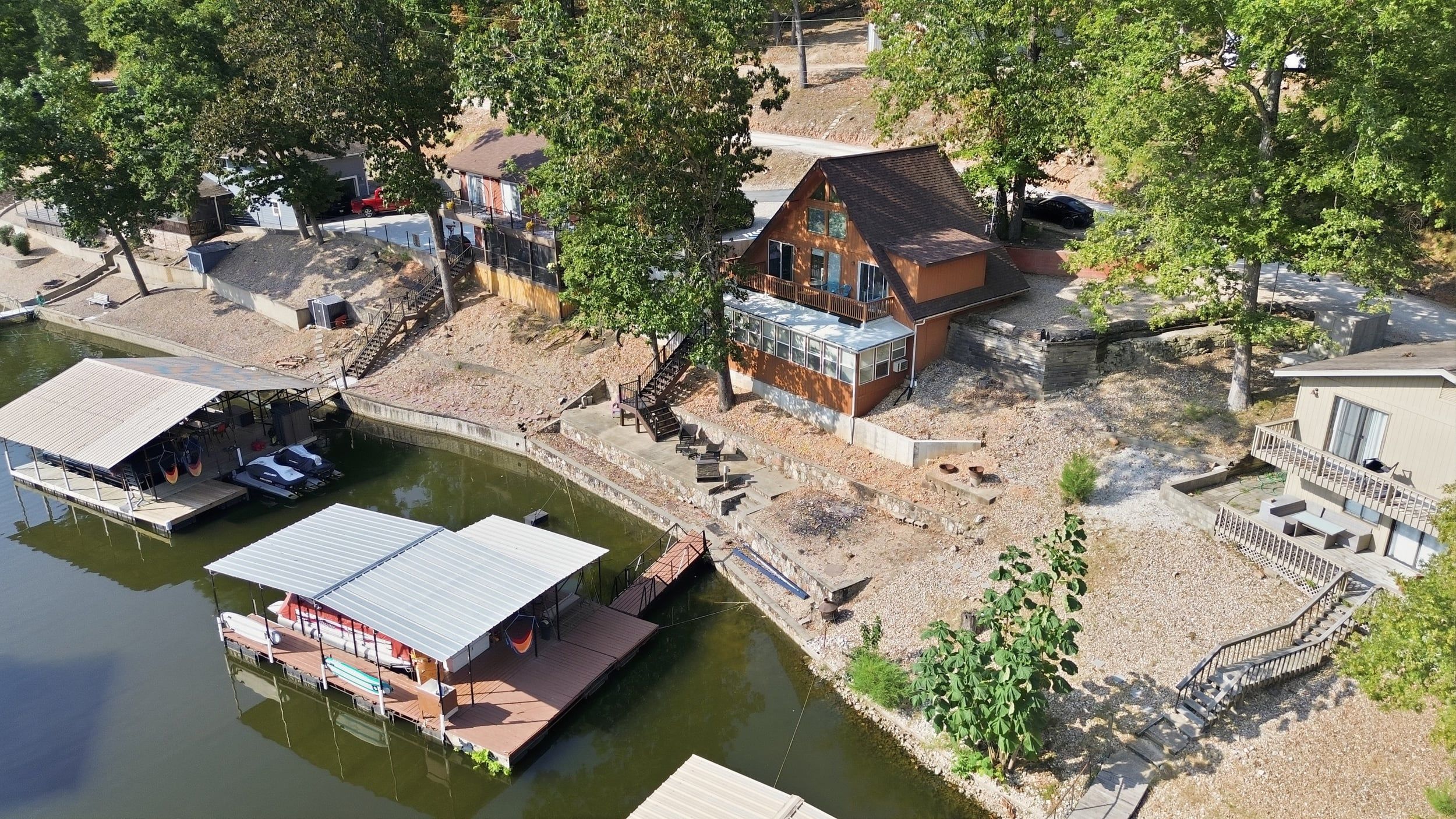 Una propiedad a orillas del río con un muelle, una casa con balcón y un pequeño jardín.