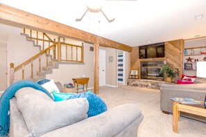 A living room with a staircase, a fireplace, and a sofa. - Quiet Cove, Lake Views, Grill, Private Dock (Sunrise Beach)