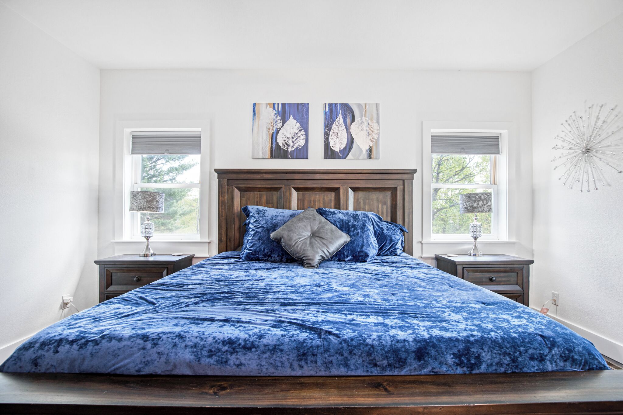 Een slaapkamer met een groot bed, twee nachtkastjes en kunst aan de muur.