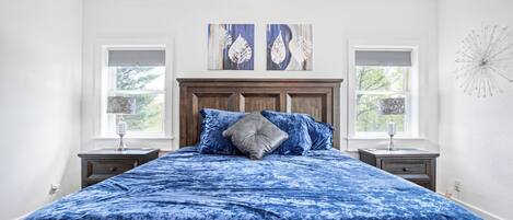 Een slaapkamer met een groot bed, twee nachtkastjes en kunst aan de muur.