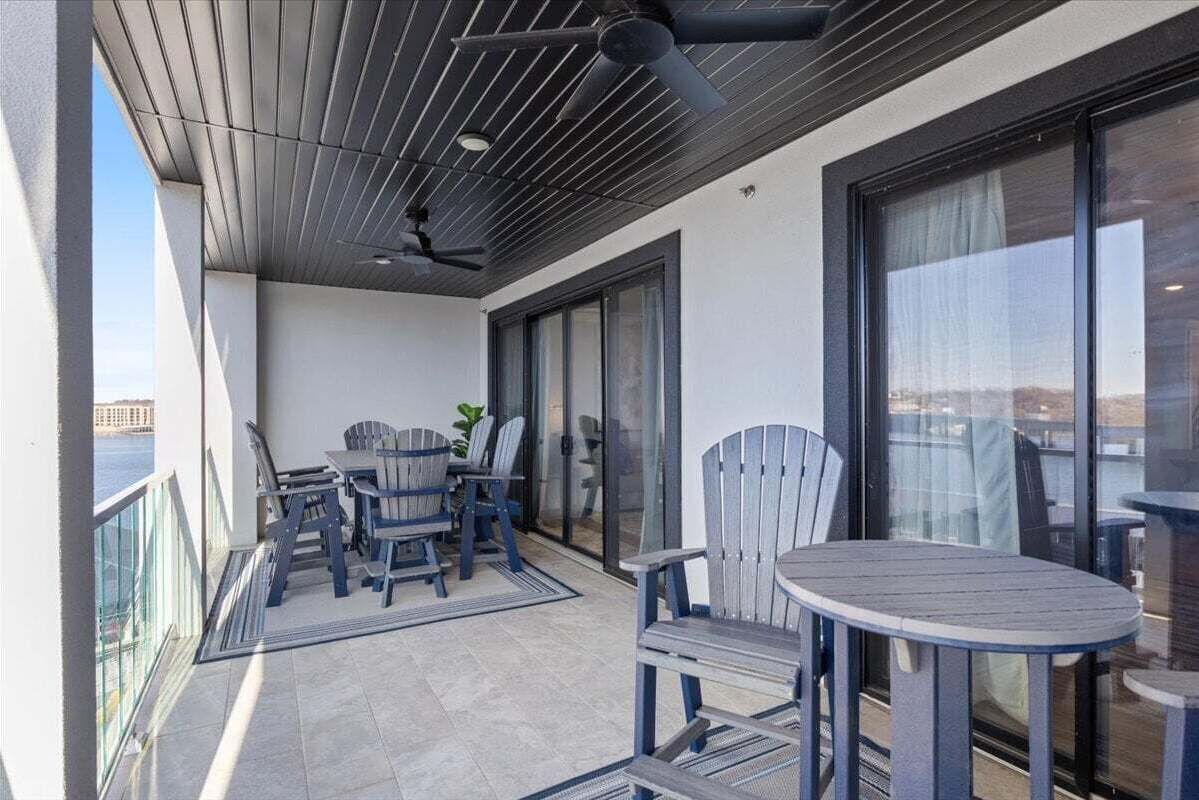 A balcony with a table and chairs, a ceiling fan, and a view of the water.