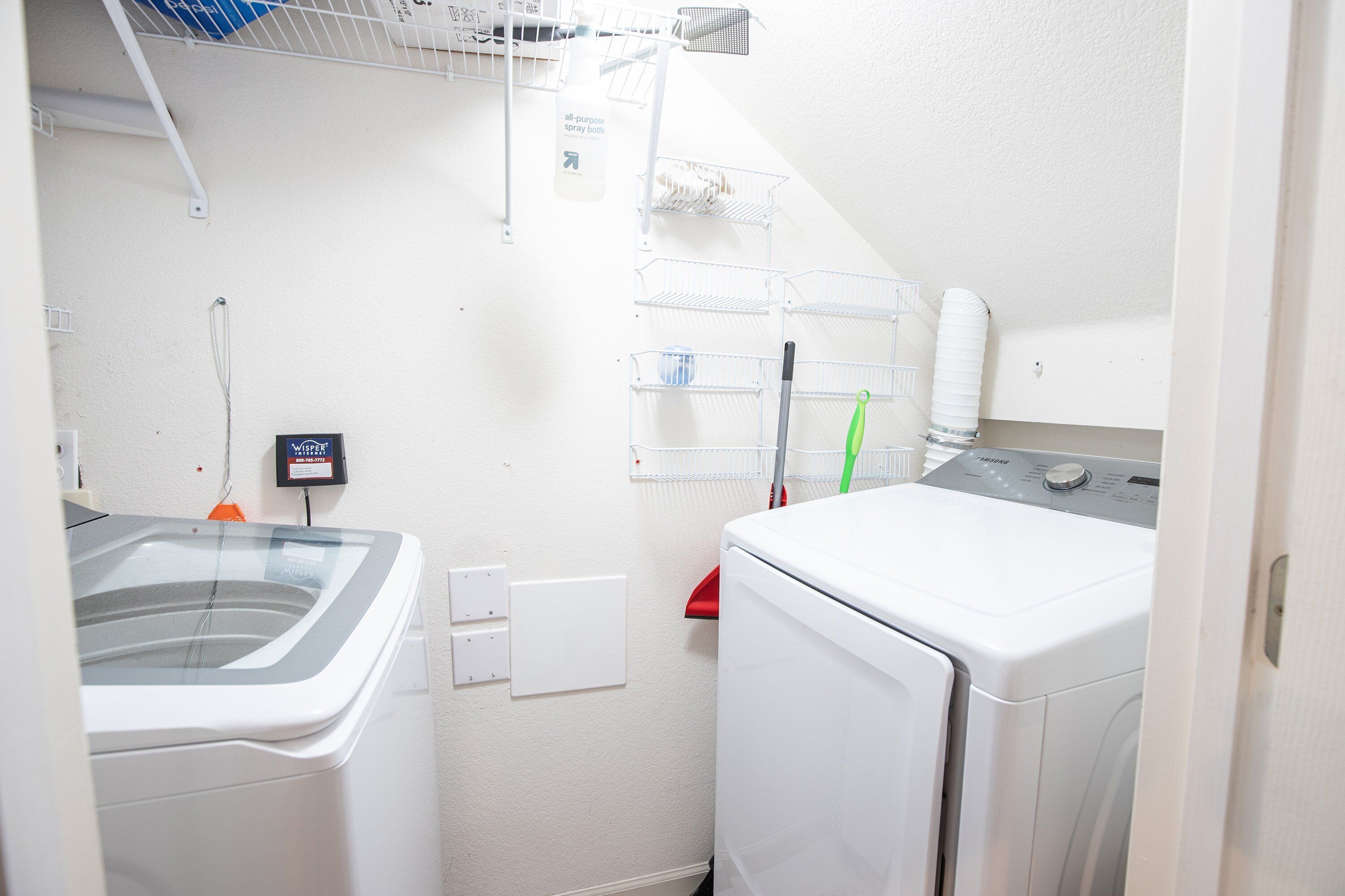 A laundry area with a washing machine, dryer, and a rack with hanging clothes.