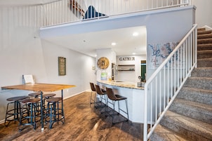 Um interior moderno com área de jantar, cozinha e escada.