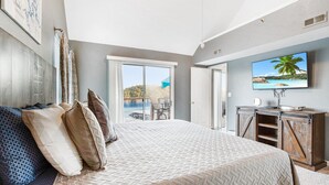 A bedroom with a large bed, a television, and a view of a pool and outdoor seating area. - Penthouse Living In The Heart of the State Park (Kaiser)