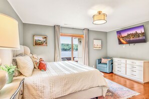 A bedroom with a bed, a TV, a dresser, and a window with curtains. - Amazing Cove, Fenced Yard, & Game Room! (Sunrise Beach)