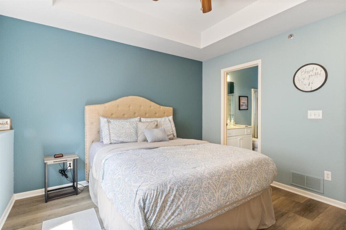 A bedroom with a bed, a nightstand, a wall clock, and a mirror.