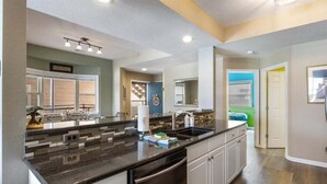 A modern kitchen with a granite countertop, stainless steel appliances, and a large island. - Lakefront 1st-floor Condo, Screened Patio, Pools & Courts (Lake Ozark)