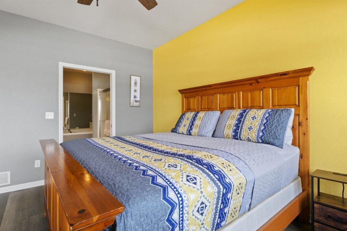 A bedroom with a wooden bed frame, a patterned bedspread, and a bench at the foot of the bed.