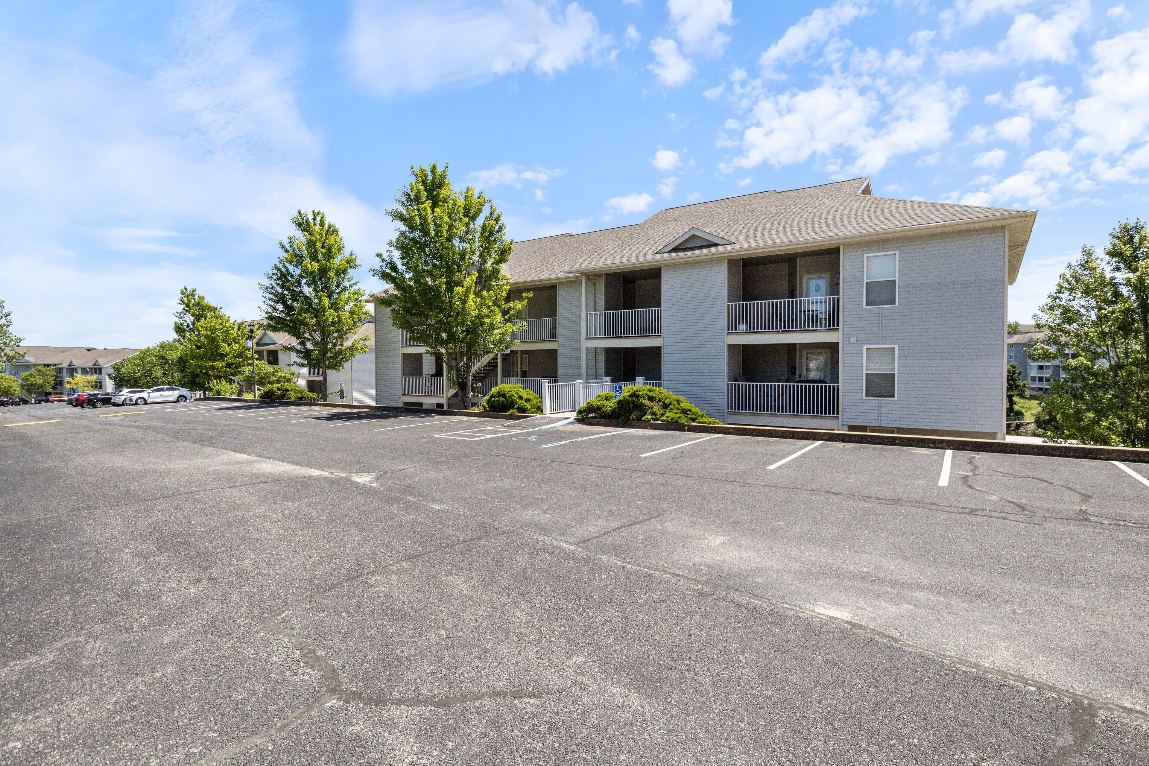 A multi-story apartment building with a parking lot in front.