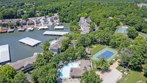 An aerial view of a residential area with houses, a swimming pool, and a tennis court. - Games, Lake Views, Ease of Access to Unit & Attractions, Family-friendly, Outdoor Comfort (Lake Ozark)