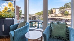 Un balcon donnant sur un pont et des immeubles, aménagé avec deux chaises bleues et une petite table.