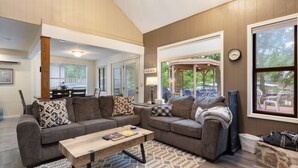 Ein großzügiges Wohnzimmer mit zwei Sofas, einem Couchtisch und Blick auf einen überdachten Außenbereich.