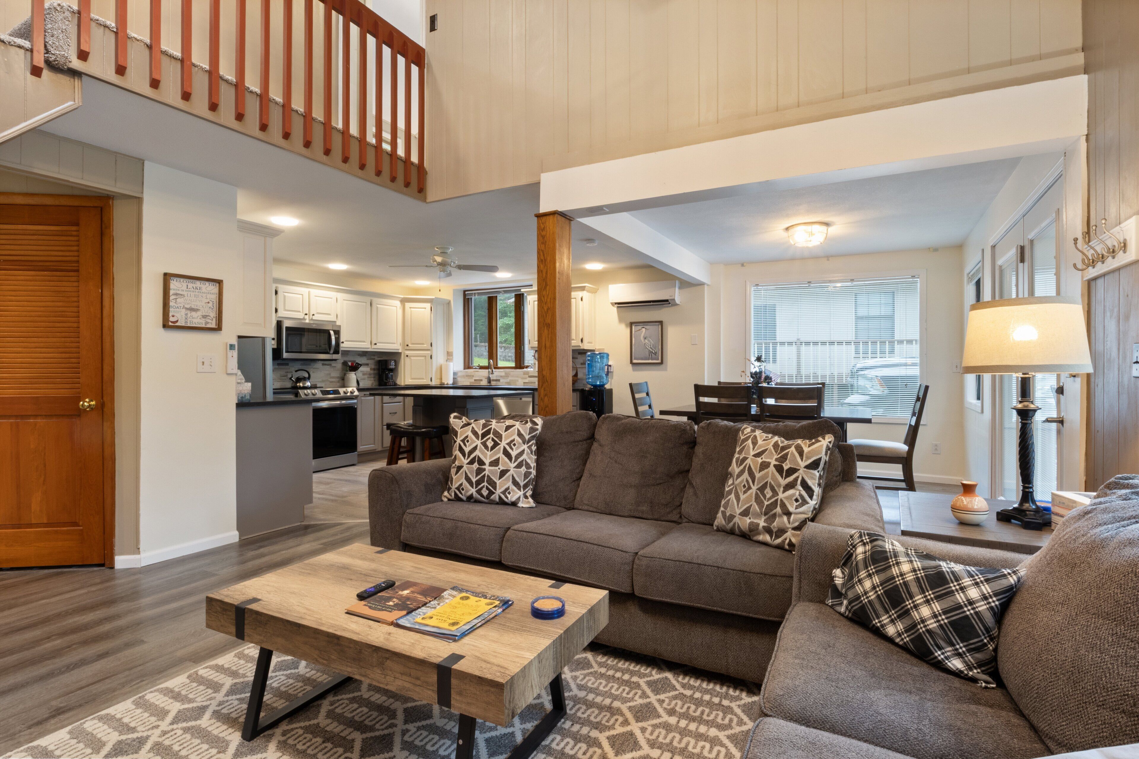 A spacious living room with a sofa, coffee table, and a dining area in the background.