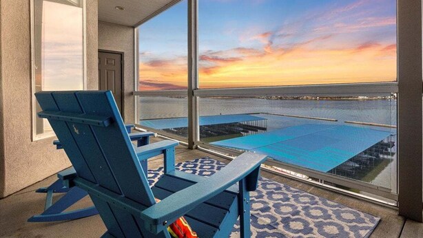 En balkon med udsigt over swimmingpool og solnedgang.