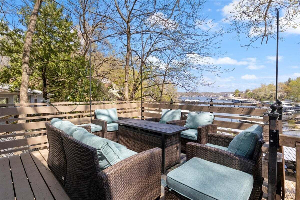 An outdoor deck with wicker furniture and a view of a river.