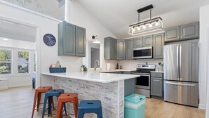A modern kitchen with grey cabinets, a white island, and stainless steel appliances.