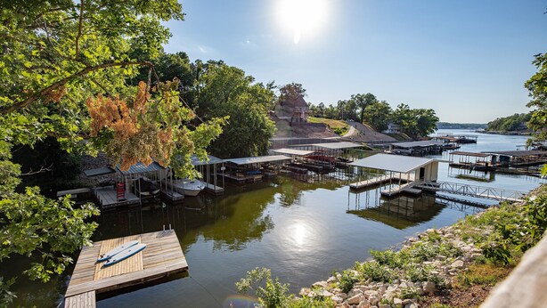A lakeside dock area with multiple docks and a small building. - Private Dock, Paddle Boards, Views & Hot Spots! (Osage Beach)