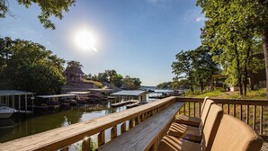 A wooden deck with seating overlooking a marina with boats and docks. - Private Dock, Paddle Boards, Views & Hot Spots! (Osage Beach)