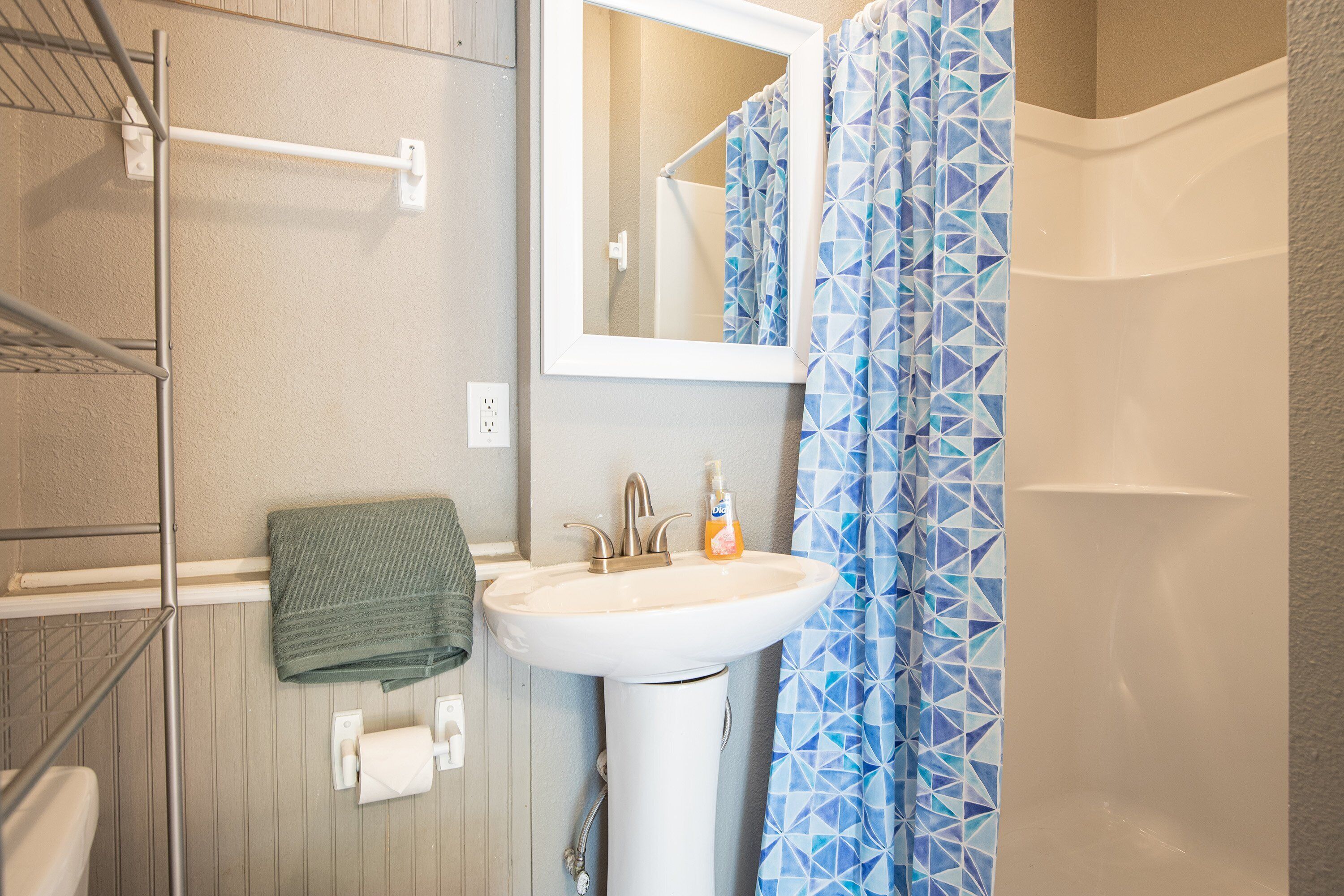 A bathroom with a white sink, a towel rack, and a shower curtain.