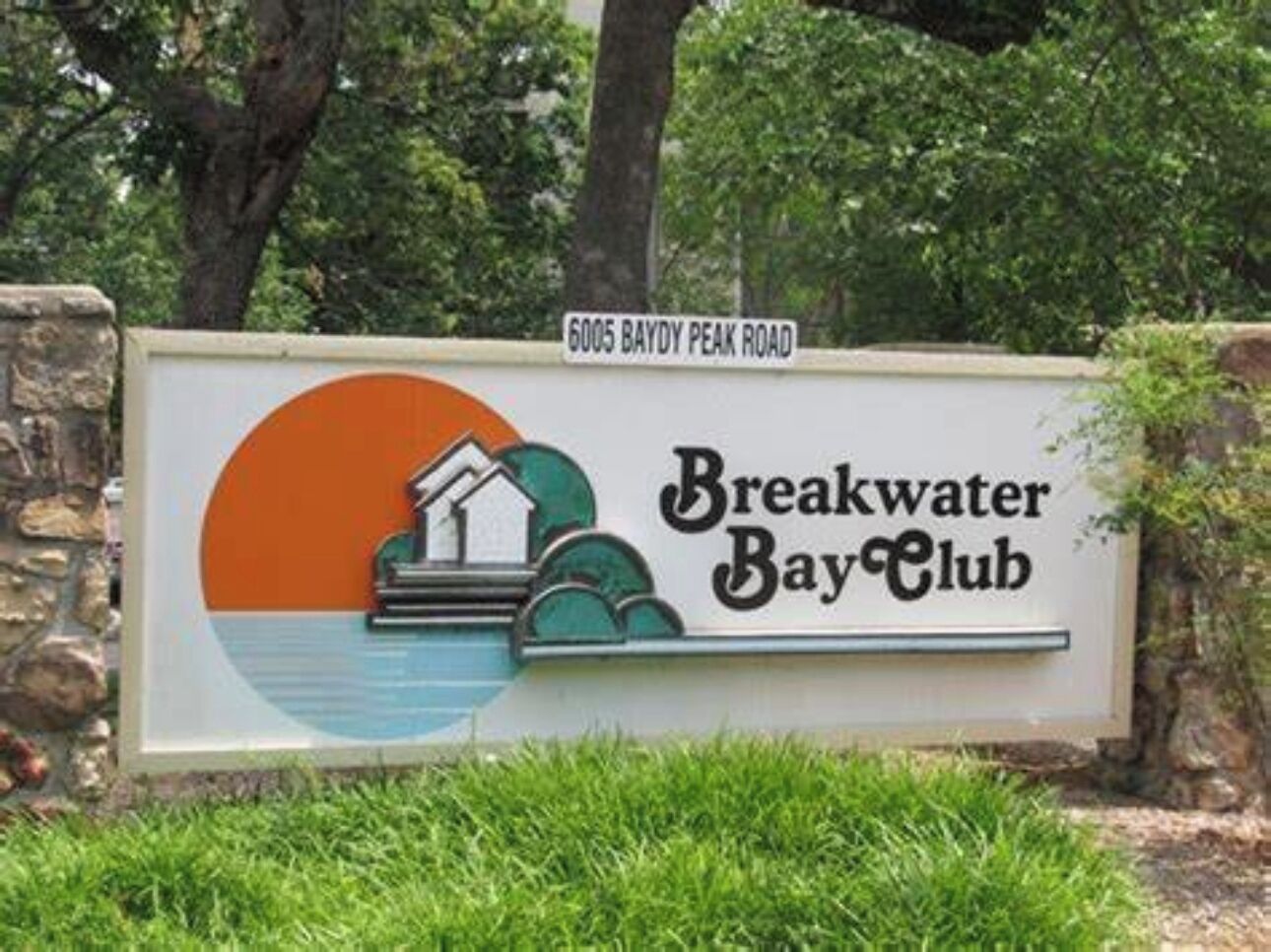 Skilt for Breakwater Bay Club med et billede af et hus og vand, beliggende på 6005 Baydy Peak Road.