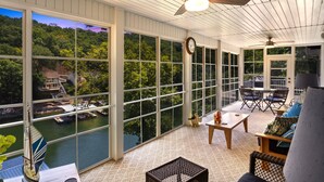 A covered patio with large windows, a ceiling fan, and a view of a dock and water. - Amazing Game Room With Dock Tram to Huge Dock - Great For Families (Lake Ozark)