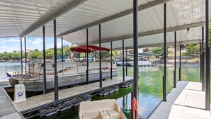 A covered boat dock with a boat and a small rowboat. - Amazing Game Room With Dock Tram to Huge Dock - Great For Families (Lake Ozark)