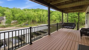 Eine überdachte Terrasse mit Geländer, einer Bank und Blick auf einen Fluss und Wald.