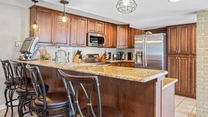 A kitchen with wooden cabinets, a granite countertop, stainless steel appliances, and bar stools. - Lake Life: Amazing Weekday Specials! Dock, Swim Mat, Cove Water (Eldon)