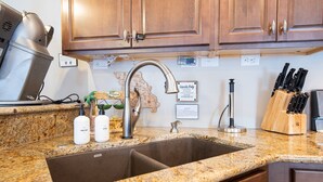 A kitchen with granite countertops, a stainless steel sink, wooden cabinets, and a knife block. - Lake Life: Amazing Weekday Specials! Dock, Swim Mat, Cove Water (Eldon)