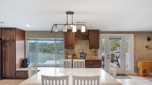 A kitchen with a large island, wooden cabinets, and a view of a lake. - Lake Life: Amazing Weekday Specials! Dock, Swim Mat, Cove Water (Eldon)