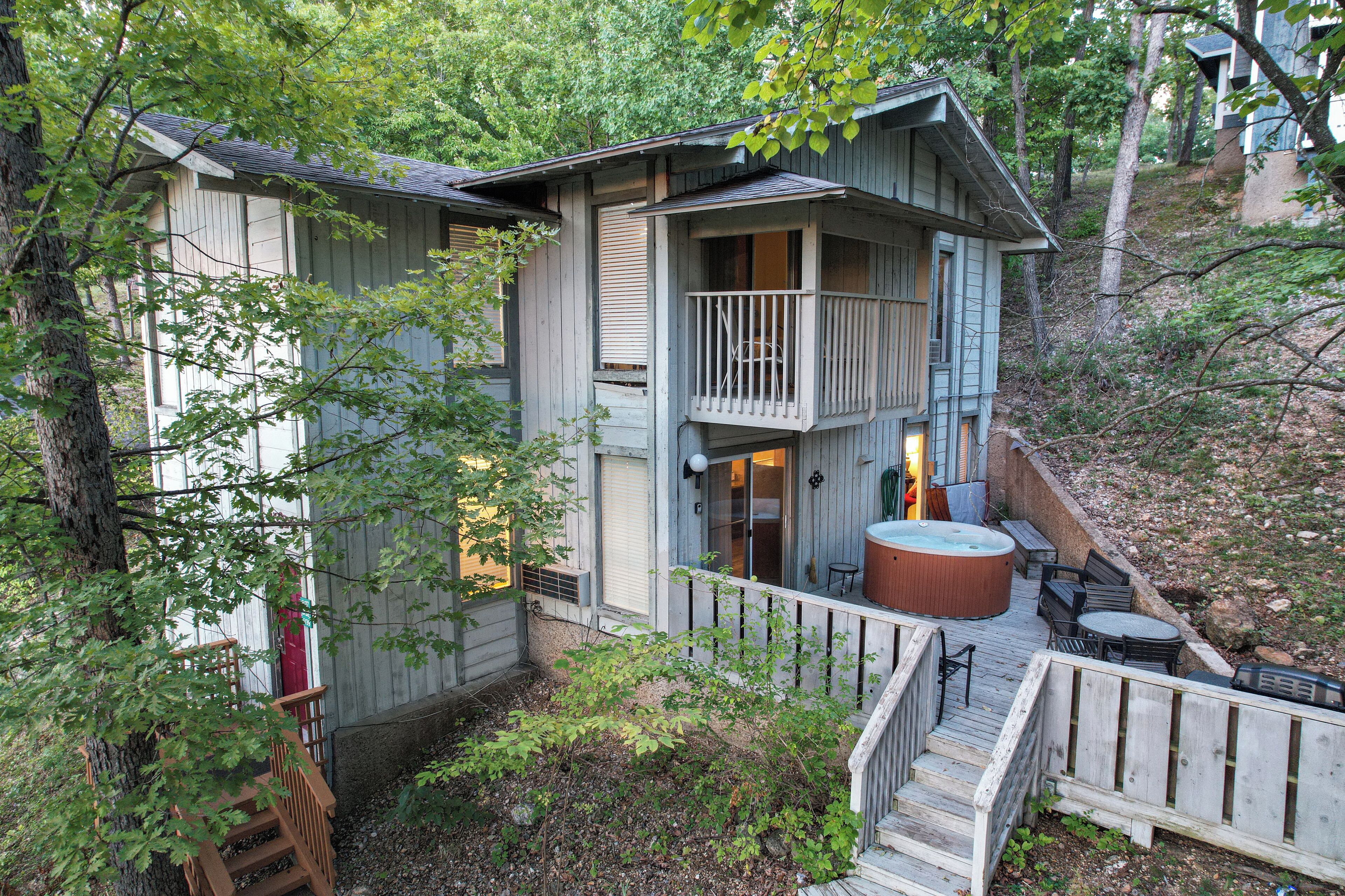 Eine zweistöckige Holzhütte mit Balkon, Whirlpool und einer Terrassenfläche.