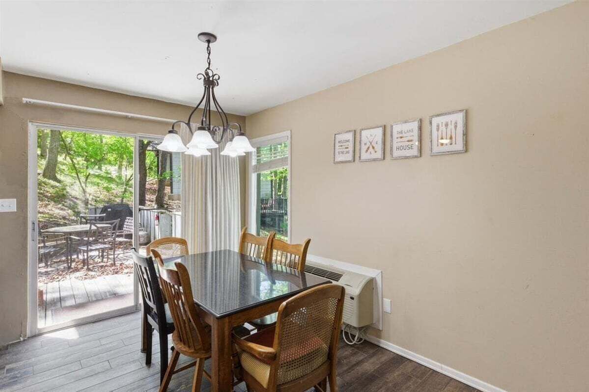A dining area with a table, chairs, a chandelier, and a view of the outdoors.