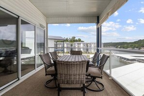 Un balcon avec une table et des chaises, d’où l’on peut admirer un plan d’eau et des bâtiments au loin.