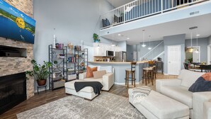Un vaste salon doté d’une cheminée, d’un plafond haut et d’une mezzanine.