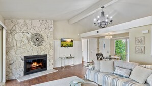 A living room with a stone fireplace, a sofa, and a television. - Perfect Resort Retreat Close to Everything (Osage Beach)