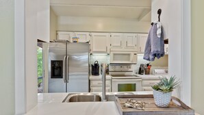 A modern kitchen with white cabinets, stainless steel appliances, a sink, and a countertop with a tray and plant. - Perfect Resort Retreat Close to Everything (Osage Beach)