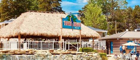 A pool area with a tiki hut and a sign that reads "TIKI HUT POOL BAR".