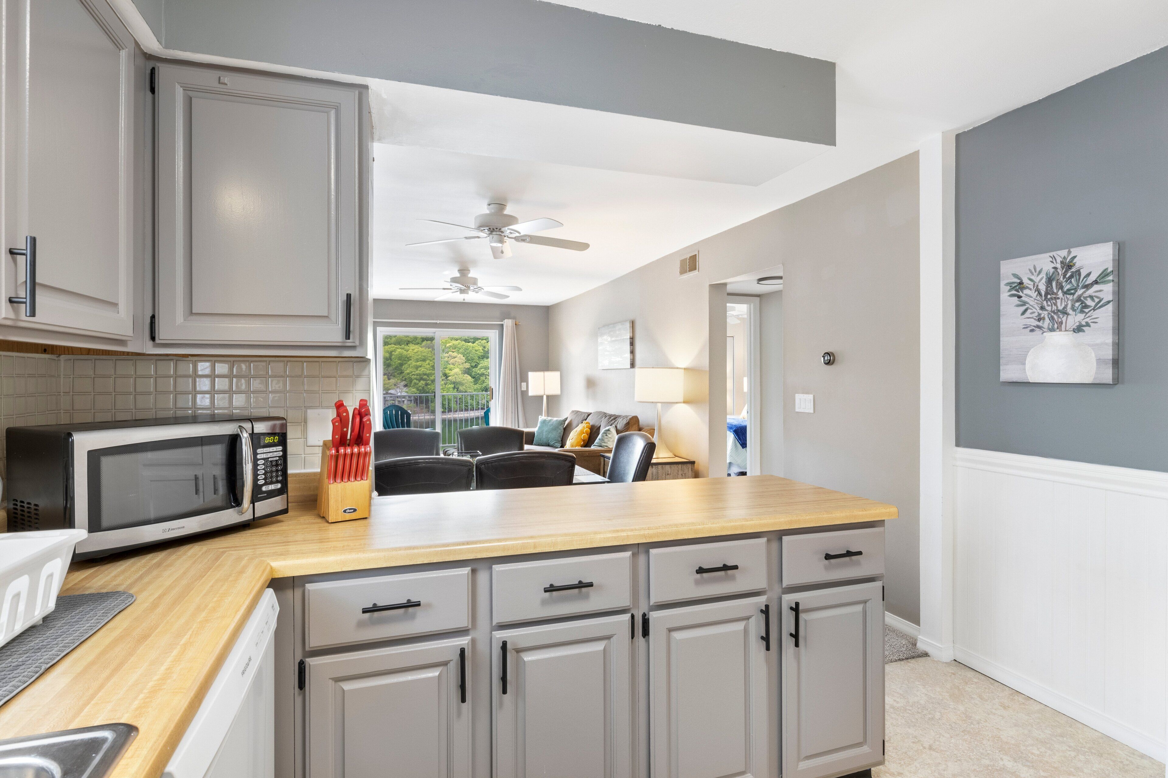 A modern kitchen with a microwave, knife block, and cabinets.