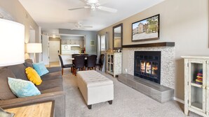 A spacious living room with a fireplace, a dining area, and a kitchen in the background. - Great Views and Pool Next to Docknockers! (Lake Ozark)