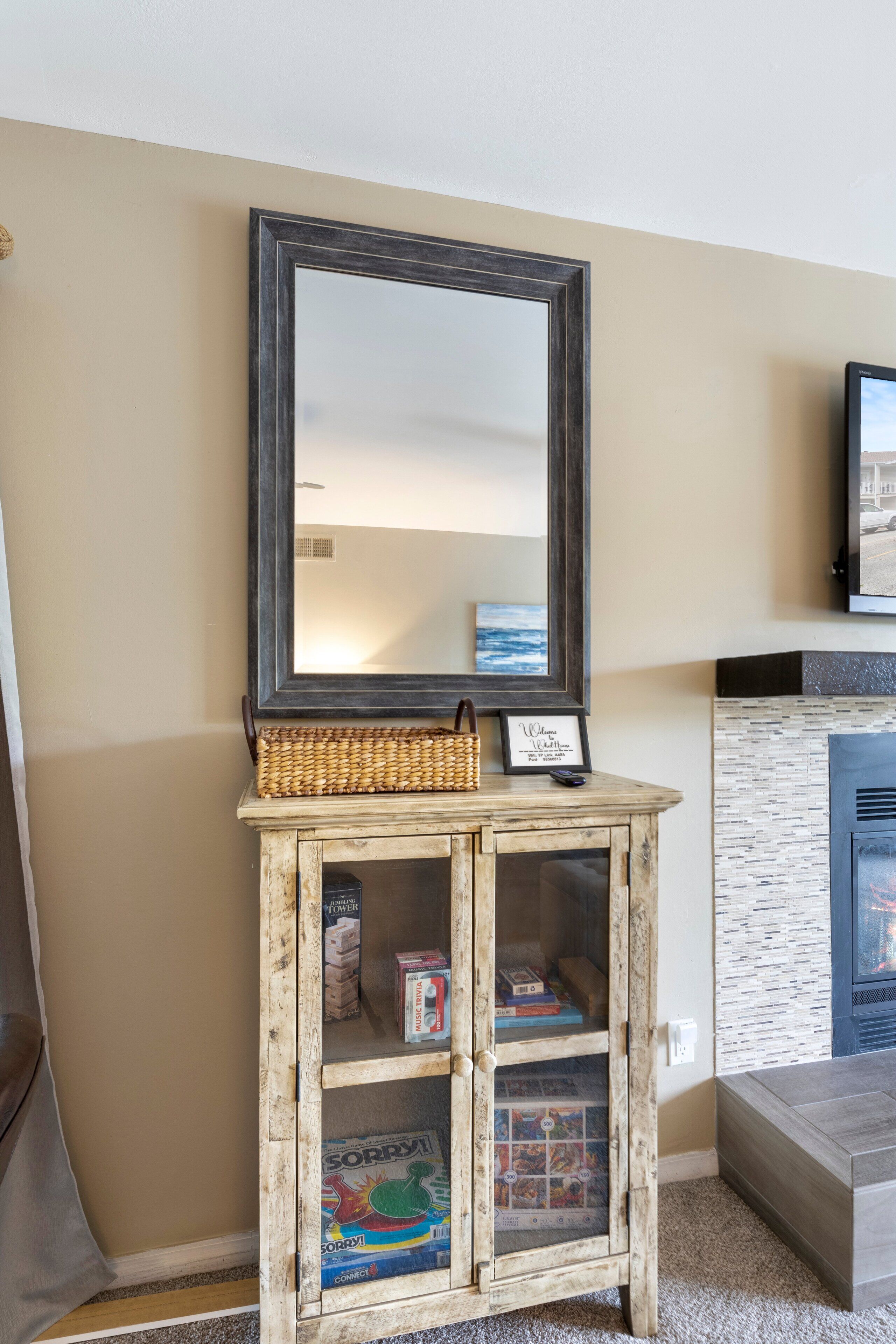 A wooden cabinet with a mirror, a welcome sign, and a woven basket.