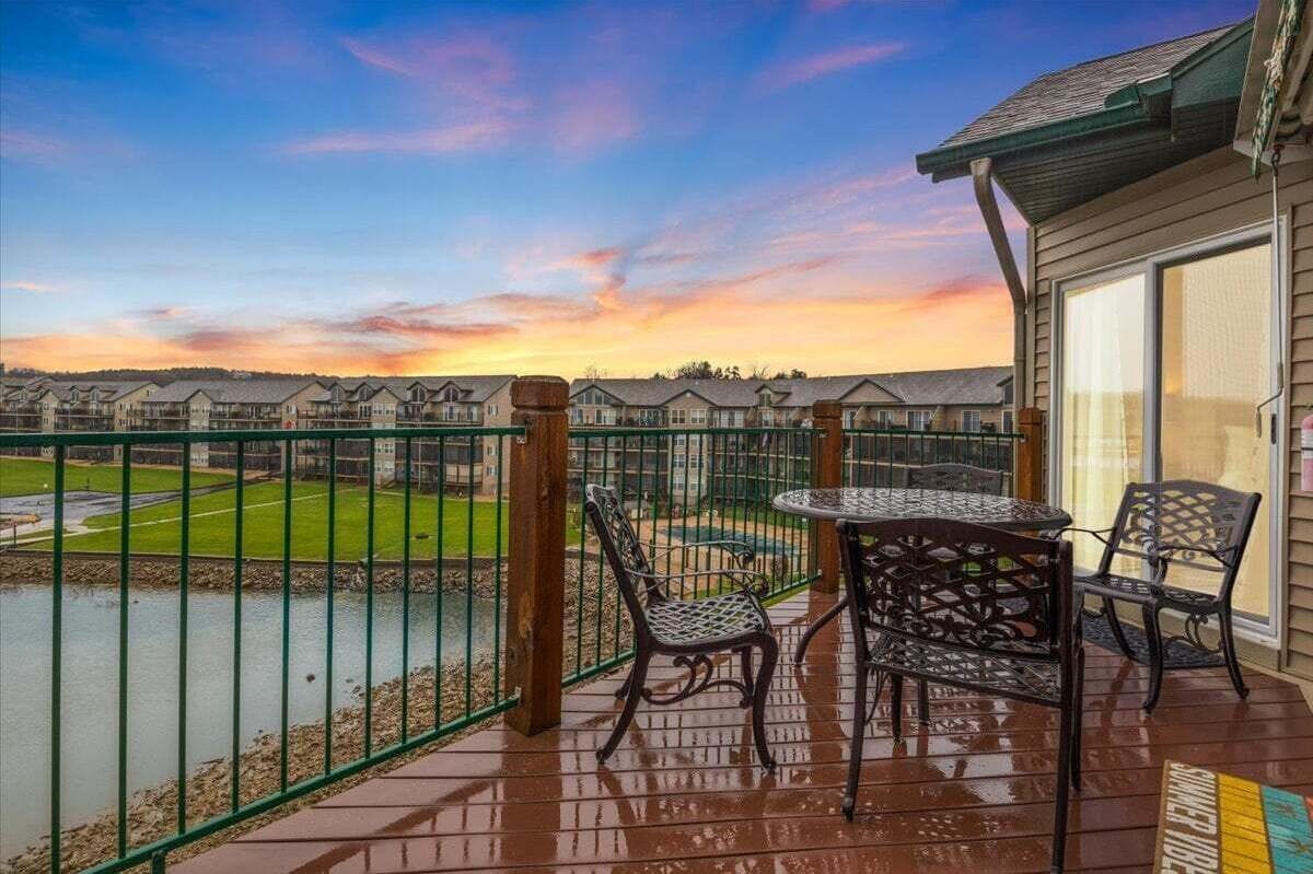 Une terrasse extérieure couverte, offrant une vue sur un terrain de golf et, au loin, sur une rangée de maisons.