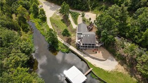 An aerial view of a riverside property with a house, a dock, and a walking path. - Newly Updated in a Private Cove, With Firepit, Flat Lawn, Dock, Boat Slip & Kayaks in Osage Beach (Osage Beach)