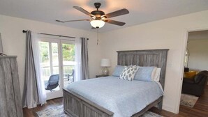 A bedroom with a bed, a ceiling fan, a nightstand, a lamp, and a view through a glass door. - Newly Updated in a Private Cove, With Firepit, Flat Lawn, Dock, Boat Slip & Kayaks in Osage Beach (Osage Beach)