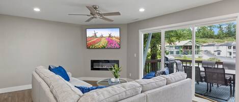 Ein modernes Wohnzimmer mit einem grauen Sofa, einem Flachbildfernseher und einem Deckenventilator.