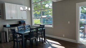 Une cuisine moderne avec des meubles blancs, un plan de travail noir et un coin repas comprenant une table et des chaises en verre.