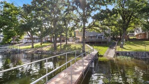 A wooden bridge over a calm water body, surrounded by trees and residential buildings. - Perfect Family House in Osage Beach With Expansive Deck, Private Dock, & Boat Slip (Osage Beach)
