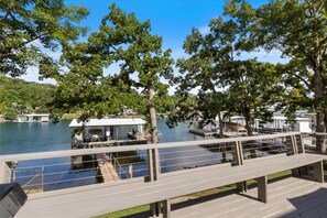 A wooden deck overlooking a lake with docked boats and a covered area. - Perfect Family House in Osage Beach With Expansive Deck, Private Dock, & Boat Slip (Osage Beach)