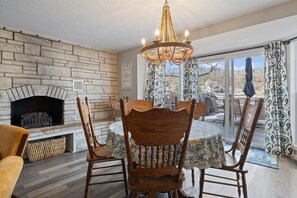 Un coin repas agrémenté d’une cheminée en pierre, de chaises en bois et d’un lustre.