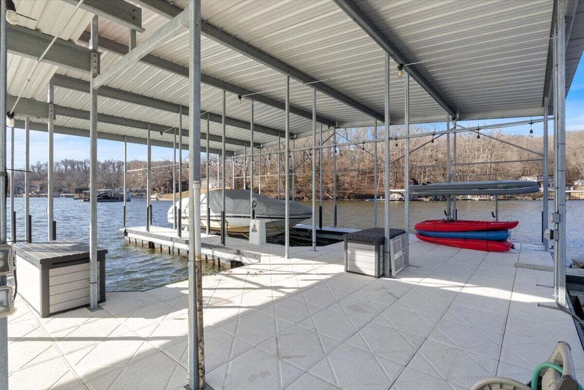 A covered boat dock with a grill and seating area, a red kayak, and a dock extending into a body of water.